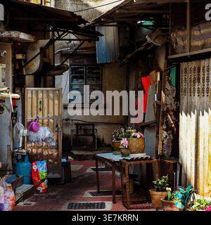 Cluttered residential back alley courtyard with weathered walls, pipes and plants in Sai Kung, Hong Kong. Stock Photo
