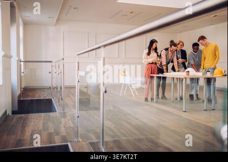 Serious Diverse group of engineers busy working on the blueprint in the table inside the working area in the office Stock Photo