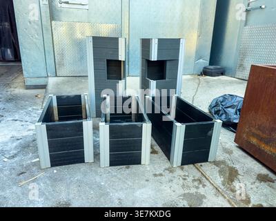 Several black wooden boxes with metal frames are placed on a concrete surface. The boxes vary in size and are arranged in an open space near a buildin Stock Photo