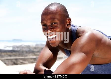 Smiling Black man looking away leaning on railing outdoors on sunny day Stock Photo