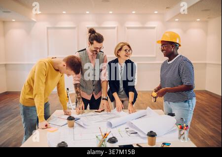 Cheerful Black woman laughing with caucasian colleague while working on the table in the office Stock Photo