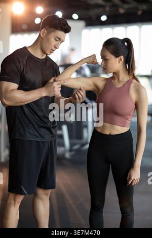 Chinese woman working out with personal trainer at gym Stock Photo