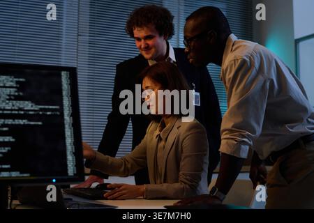 Diverse group of programmers developing new code for computer program together working overtime in office Stock Photo