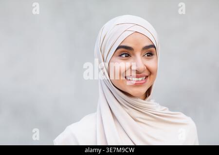Beautiful model, blogger, student with positive facial expression, video call. Head shot of happy young pretty cute middle eastern female in hijab ove Stock Photo