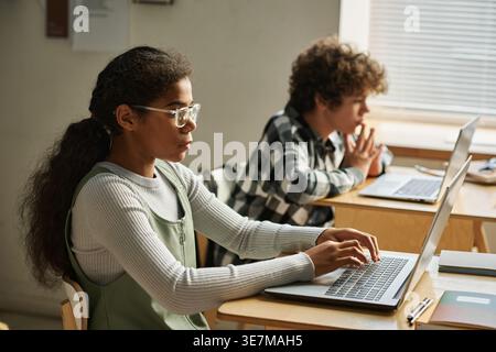 Diverse group of students working on laptop in computer lab during daytime Stock Photo