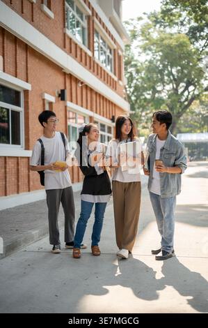 Smiling group of Asian college students talking standing on hallway outside the building campus after classes during daytime Stock Photo
