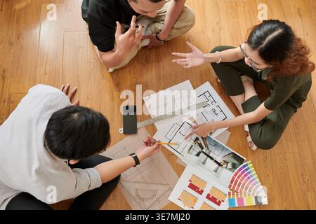 Team of Asian architects discussing work sitting at table in office Stock Photo