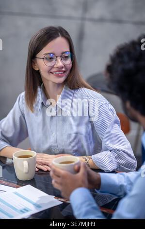 Indian businessman talking to female colleagues having coffee sitting at table in restaurant Stock Photo