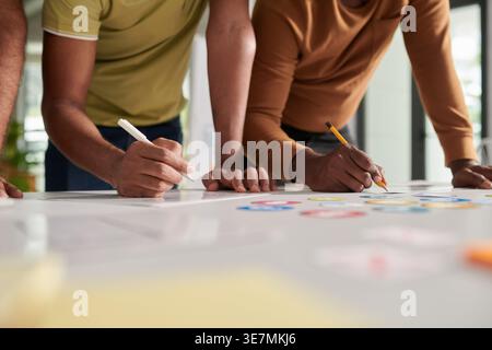 Indian male UI and designers standing and leaning forward on table working on interface and icon for new mobile app in office Stock Photo