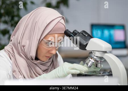 Serious Mixed race female scientist putting a sample on microscope in the laboratory clinic Stock Photo