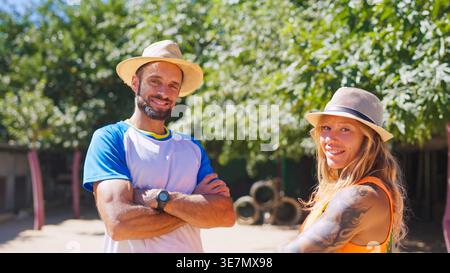Smiling couple wearing hats standing outdoors in summer sunshine Stock Photo