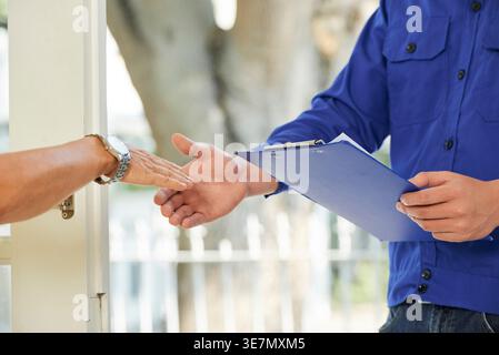 Cropped image of Asian repairman shaking hand with mature female client outdoors Stock Photo