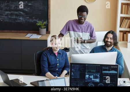Group of programmers looking at computer screen discussing their work ideas in office workplace Stock Photo