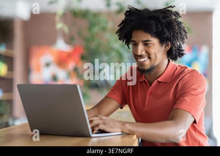 Black male with afro using laptop sitting at table in cafe Stock Photo