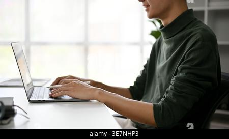 Asian male working on laptop while sitting at table at home Stock Photo