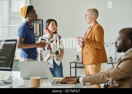 Diverse group of programmers discussing new project while standing in office Stock Photo