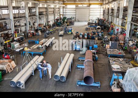 Hispanic male manager discussing plans to team of workers standing in factory Stock Photo