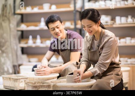 Chinese man teaching her wife making ceramic pot from clay in pottery workshop Stock Photo