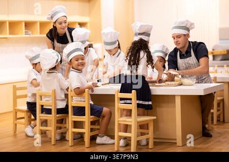Chinese children learning how to cook with Chinese female and caucasian male teachers in school Stock Photo