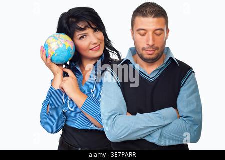 Woman holds globe, smiling confidently. Man stands beside her, arms crossed, expression weary. Their contrasting poses suggest global perspective vers Stock Photo