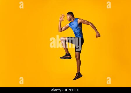 Black man jumping against yellow background in studio Stock Photo