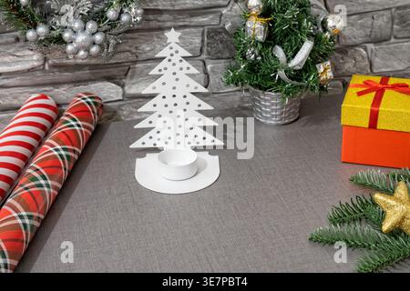 Festive setting with Christmas decorations, gift boxes, and wrapping paper arranged on a table during the holiday season Stock Photo