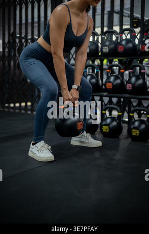 Cropped image of Thai woman exercising with kettlebell in gym Stock Photo