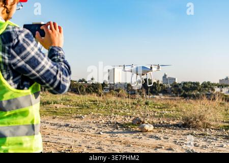 Drone operated by Middle Eastern male construction worker standing on construction site during daytime Stock Photo