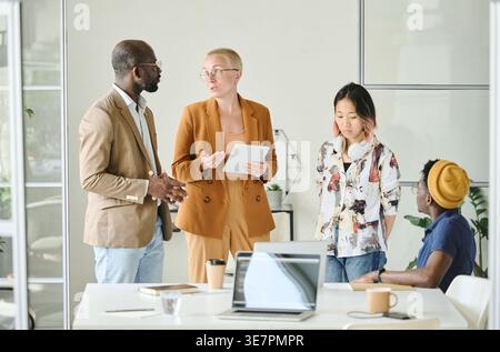 Diverse group of programmers discussing new project while standing in office Stock Photo