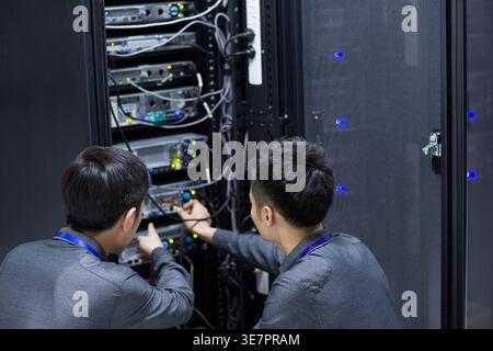 Chinese male technicians doing maintenance in computer room Stock Photo