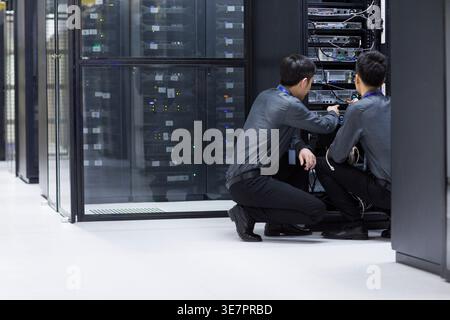 Chinese male technicians doing maintenance in computer room Stock Photo