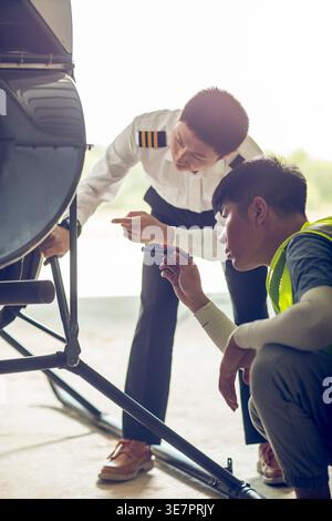 Chinese airplane mechanic checking helicopter with his apprentice in airport Stock Photo