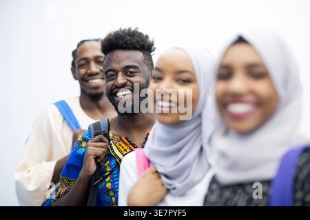 Smiling Black and Muslim college students standing with backpacks against white background in studio Stock Photo