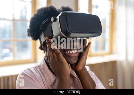 Black woman with afro experiencing VR glasses standing in kitchen at home Stock Photo