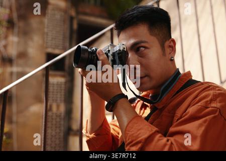 Asian male photographer holding camera taking photo in abandoned building Stock Photo