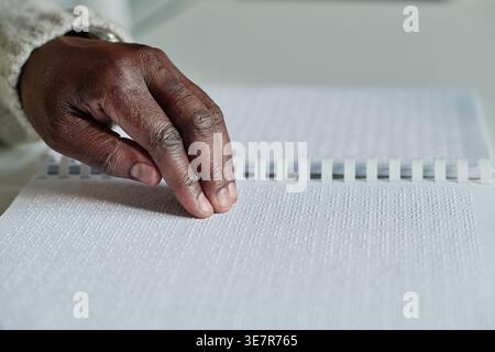 Hand of Black man reading braille at table at home Stock Photo