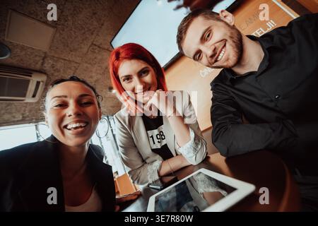 Smiling Diverse group of business people sitting together at table with tablet in cafe Stock Photo