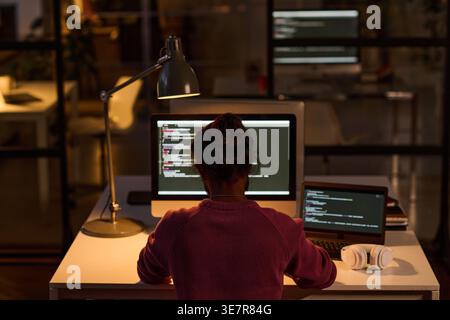 Indian male programmer examining computer codes sitting at table working late at night in office Stock Photo
