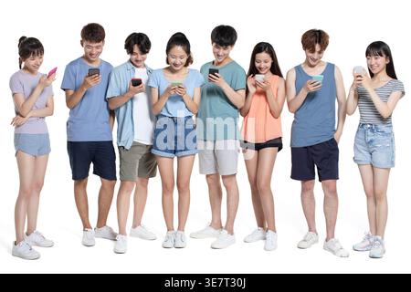 Cheerful Chinese male and female colleges students using smartphones standing against white background in studio Stock Photo