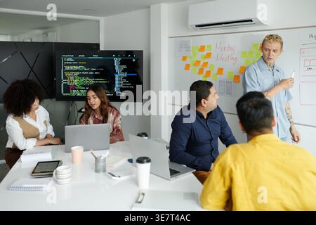 Group of developers working as team on new big project discussing programming code in office Stock Photo
