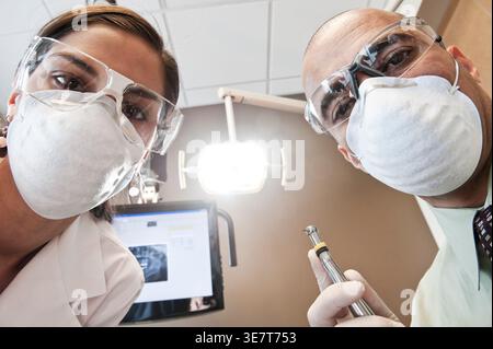 Hispanic female dentist and Middle Eastern male dentist checking patient in clinic Stock Photo
