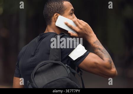 Sporty Man With Backpack Talking On Phone After Workout Outdoors Stock Photo