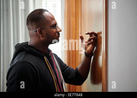 Asian male software developer knocking at door of his team leader in office Stock Photo