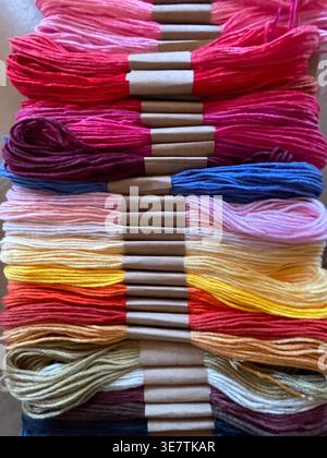 Close-up of vibrant multicolored embroidery floss skeins arranged in neat rows, showing a rich spectrum of bright colors. Stock Photo