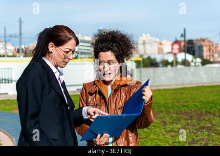 Business women discussing report during outdoor city meeting Stock Photo