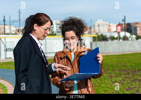 Mature businesswomen discussing outdoor project presentation in city Stock Photo