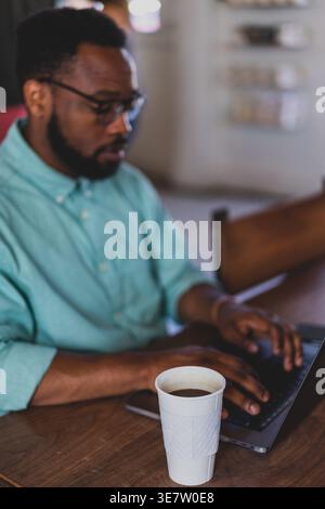 Black male professional typing on a laptop at a coffee shop Stock Photo