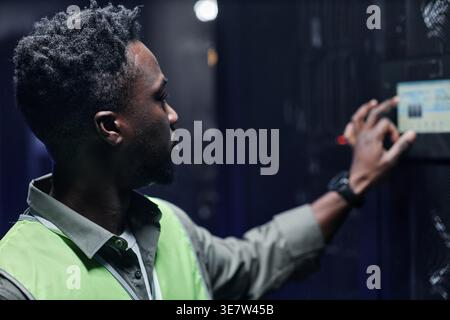 Black male network technician standing and doing maintenance work in server room Stock Photo