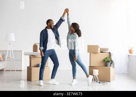 Black couple dancing in living room near unpacked boxes at home Stock Photo