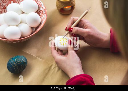 Lithuanian girl painting traditional Easter eggs with hot beeswax using a needle Stock Photo